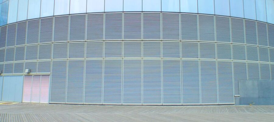Contemporary glass building wall with aluminum solar facade shading panels on clear sunny day
