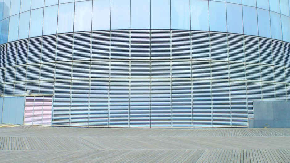 Contemporary glass building wall with aluminum solar facade shading panels on clear sunny day