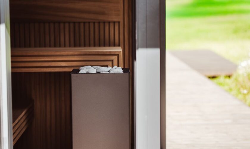 Contemporary outdoor sauna featuring wood panels and an electric heater with stones.