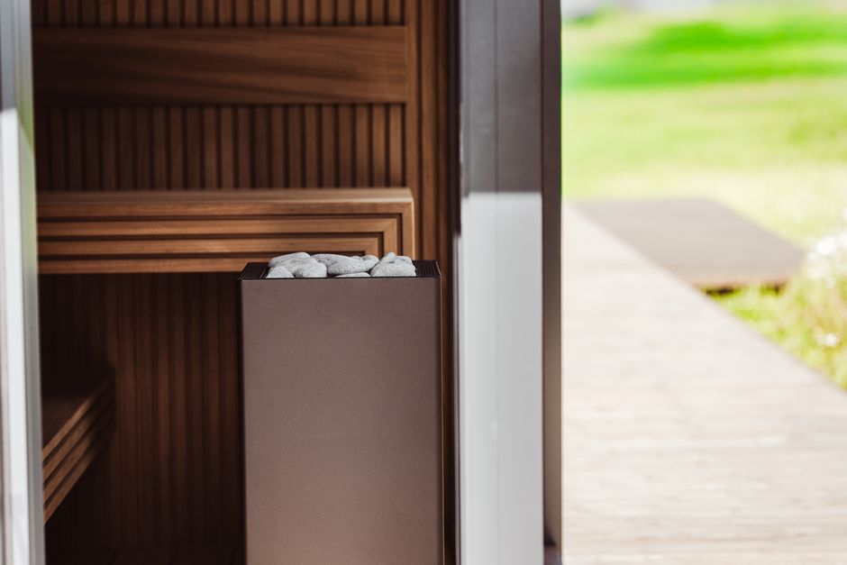 Contemporary outdoor sauna featuring wood panels and an electric heater with stones.
