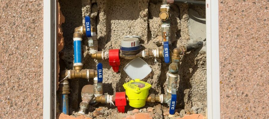 Detailed view of a complex water meter setup embedded in a concrete wall.