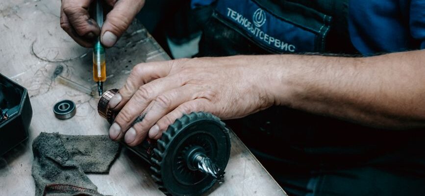 Detailed view of a technician working on a mechanical gear part with precision tools on a workbench.