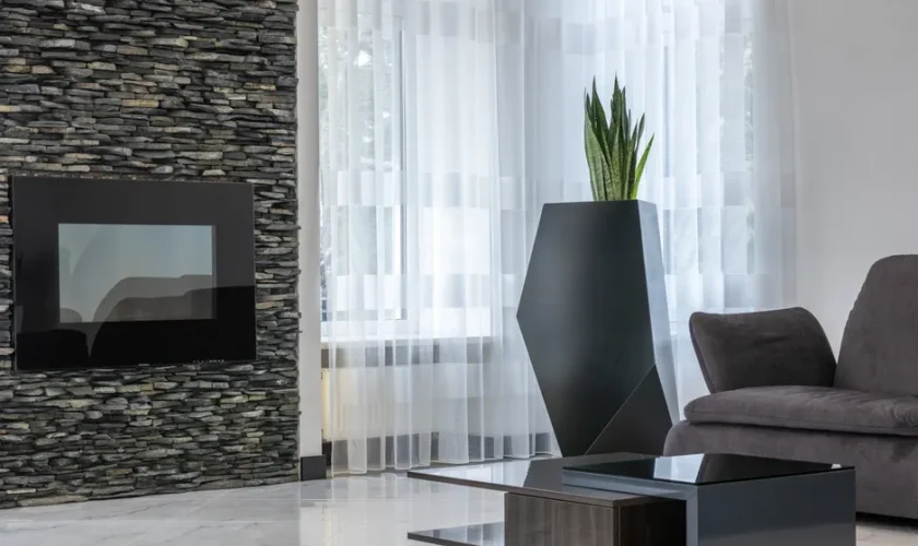 Electric fireplace on creative stone wall in spacious modern living room with cozy sofa and exotic potted plant