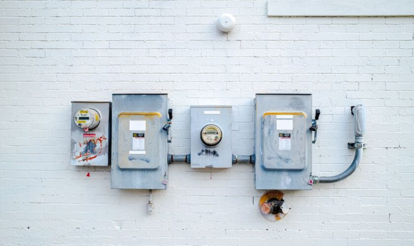Electrical boxes and power meters mounted on a white brick wall.