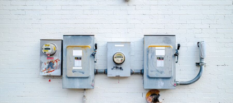 Electrical boxes and power meters mounted on a white brick wall.