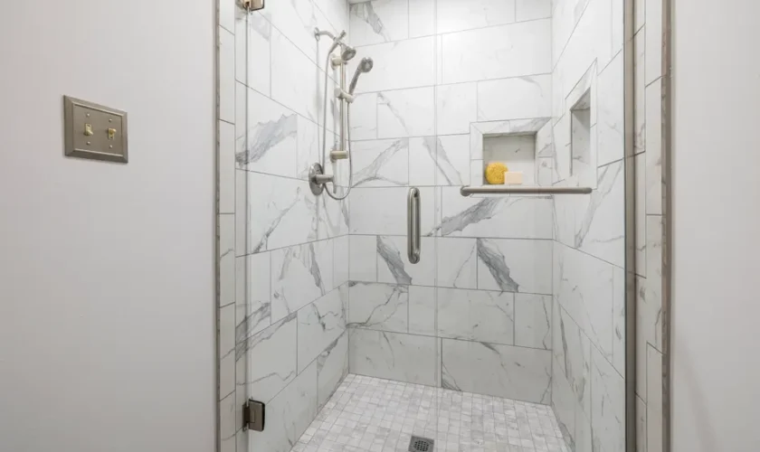 Elegant bathroom with white marble tiles and glass door, showcasing modern interior design.