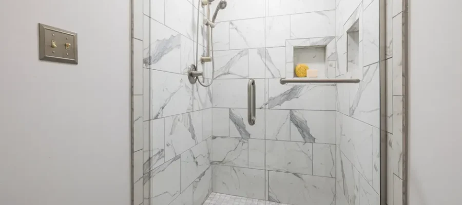 Elegant bathroom with white marble tiles and glass door, showcasing modern interior design.