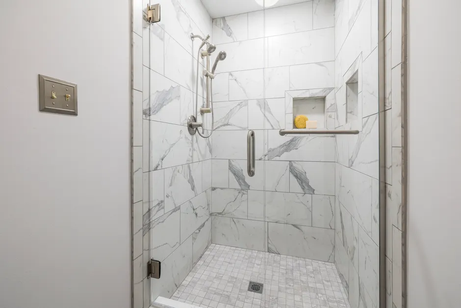 Elegant bathroom with white marble tiles and glass door, showcasing modern interior design.