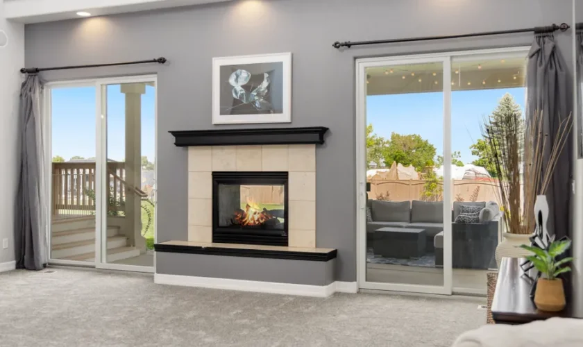 Elegant living room interior with a fireplace, gray walls, and sliding doors leading to a patio.