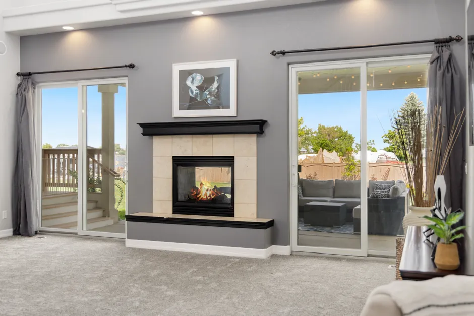 Elegant living room interior with a fireplace, gray walls, and sliding doors leading to a patio.