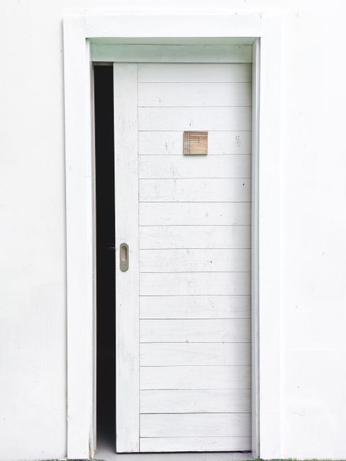 Elegant minimalist design featuring a white sliding door slightly open on a white wall, perfect for modern architecture concepts.