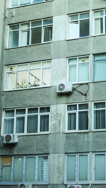 Facade of an urban building with air conditioners and windows in view.