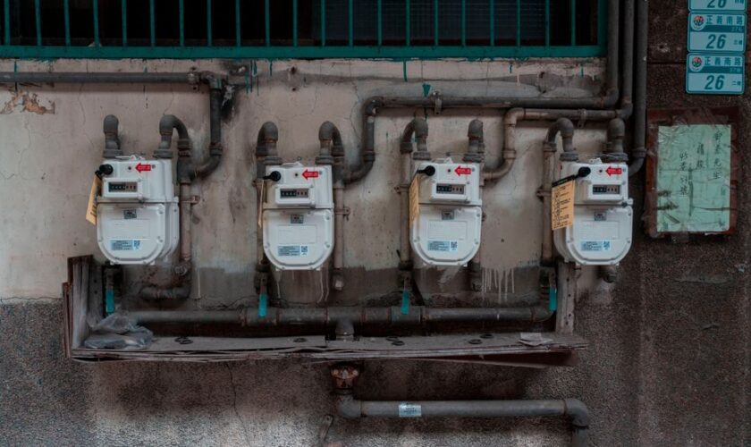 Four gas meters mounted on an exterior wall, showcasing urban utility infrastructure.