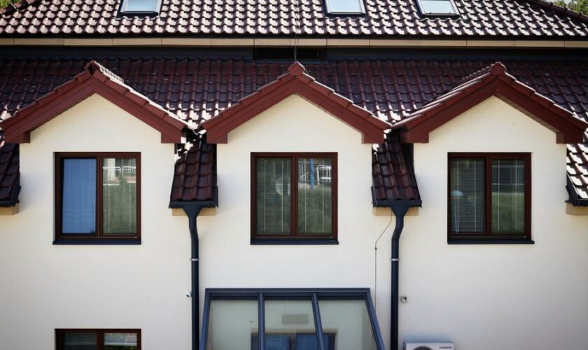 Front view of a modern house with a red tiled roof and multiple windows.
