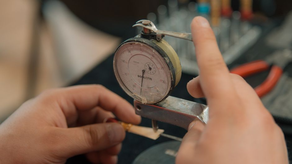 Hands measuring with an analog dial indicator for precision work.
