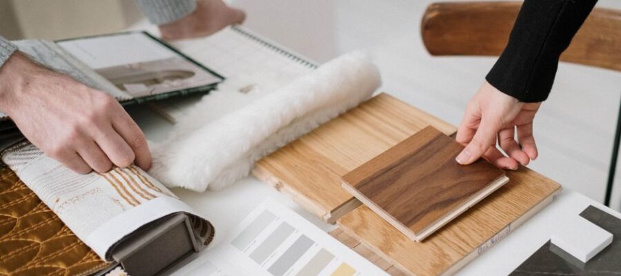 Hands selecting and comparing textile and wood samples for interior design.