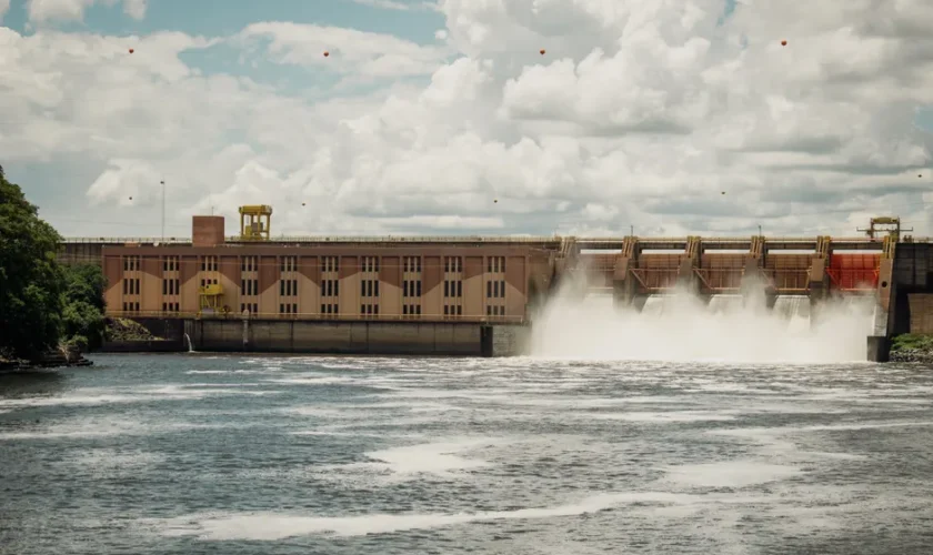 Hydroelectric dam releasing water under a dramatic cloudy sky.