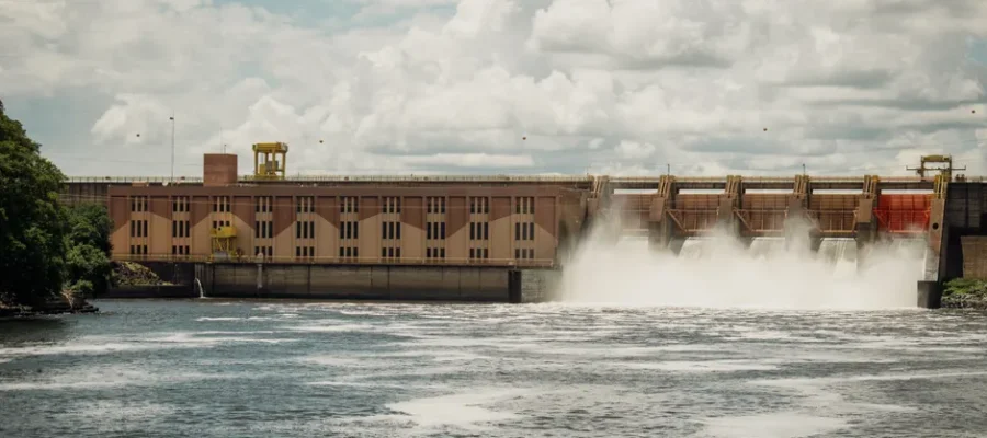 Hydroelectric dam releasing water under a dramatic cloudy sky.