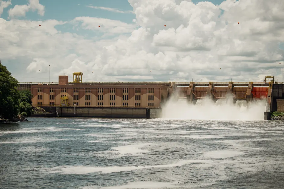 Hydroelectric dam releasing water under a dramatic cloudy sky.