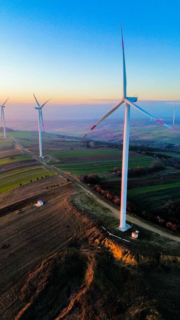 Majestic wind turbines in a vibrant landscape at sunset, showcasing renewable energy sources.