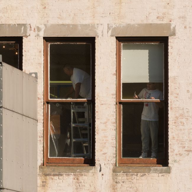 Men seen through windows working on interior renovations in a New York City building.