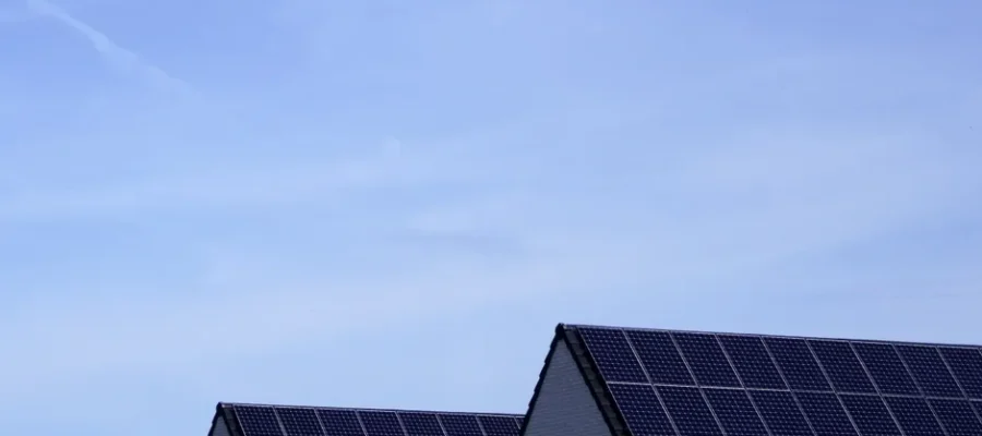 Modern Belgian houses with solar panels on rooftops under a clear blue sky.