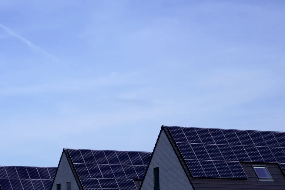 Modern Belgian houses with solar panels on rooftops under a clear blue sky.
