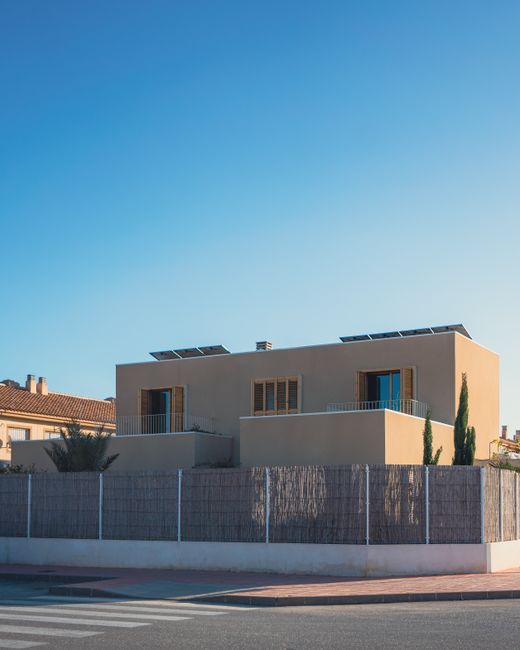 Modern suburban house featuring solar panels on the roof, bathed in daylight.