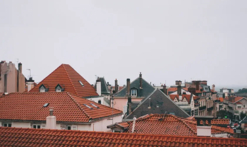 Old dwelling building roofs with ribbed tiles and attic windows in city in daylight