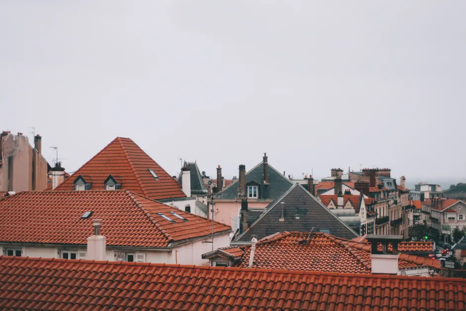 Old dwelling building roofs with ribbed tiles and attic windows in city in daylight