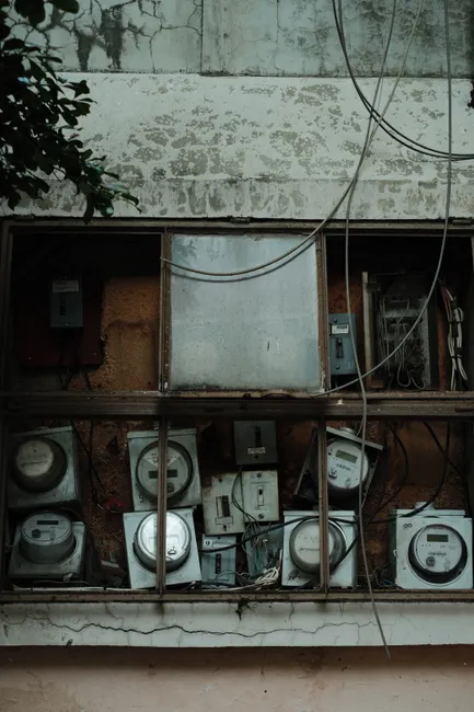 Old electric meters on a crumbling building in Guadalajara, Mexico, displaying urban decay.
