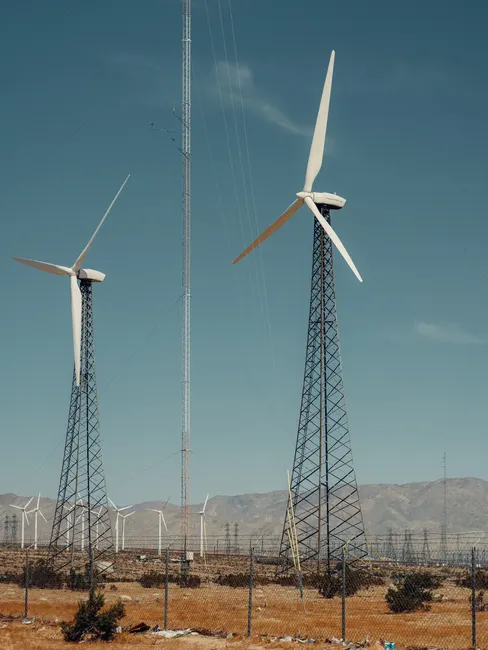 Row of wind turbines in a dry landscape, highlighting renewable energy in action under a clear sky.