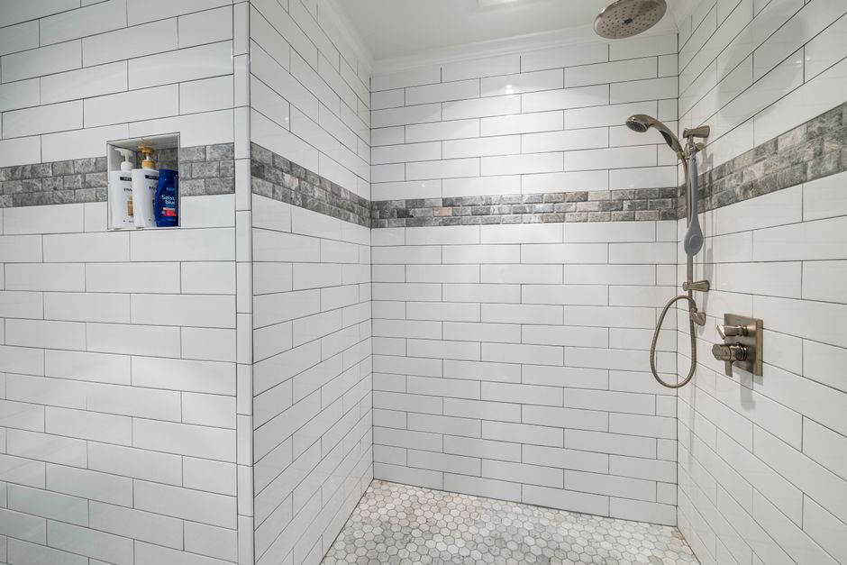 Spacious modern bathroom with white tiles and sleek shower design.