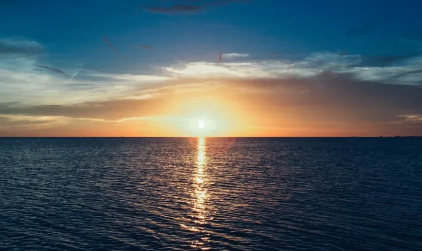 Stunning sunset over the ocean with vibrant colors and a calm sea reflecting the light.