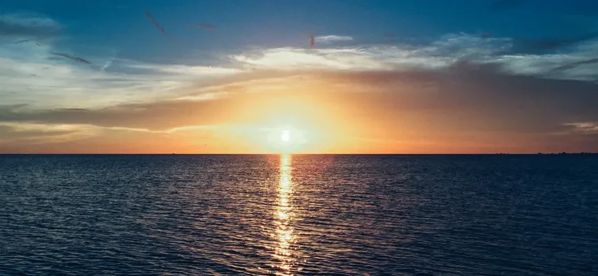 Stunning sunset over the ocean with vibrant colors and a calm sea reflecting the light.