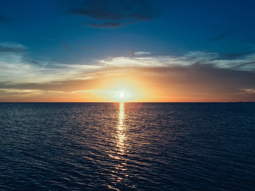Stunning sunset over the ocean with vibrant colors and a calm sea reflecting the light.