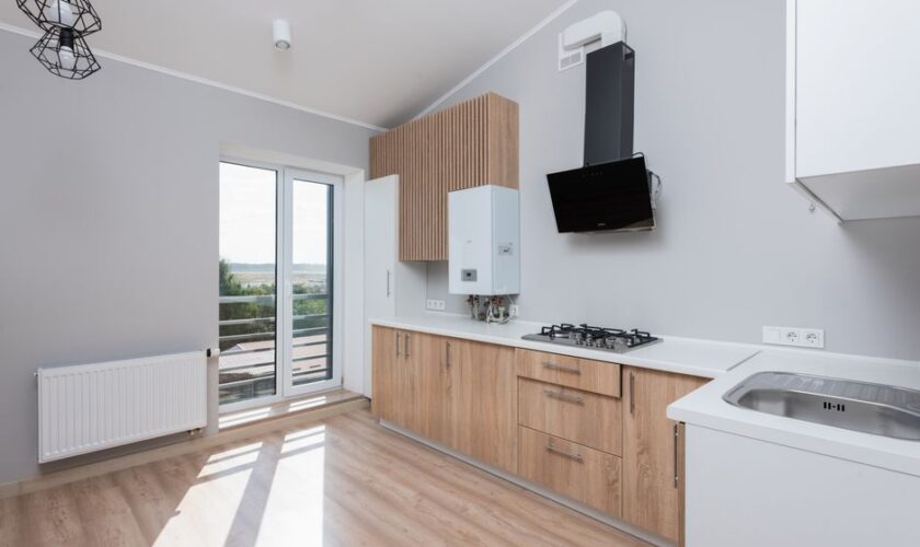 Stylish empty kitchen with wooden cabinets and large windows.