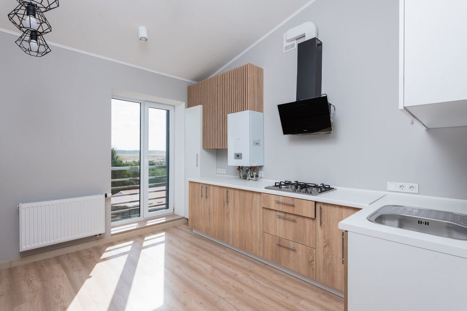 Stylish empty kitchen with wooden cabinets and large windows.
