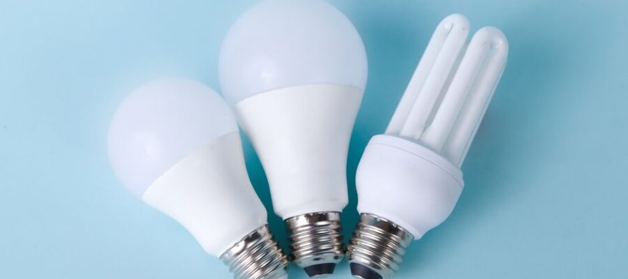Three assorted LED and CFL light bulbs against a light blue background.