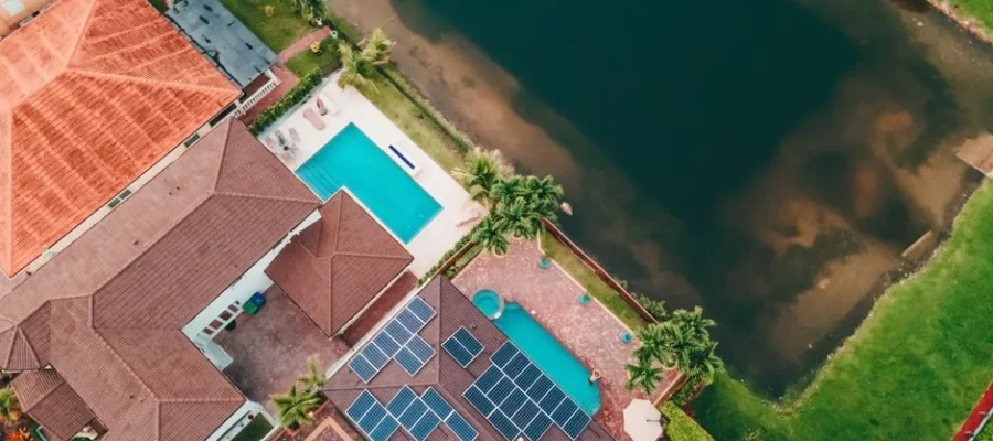 Top-down view of a Miami home with solar panels and pool near a lake.