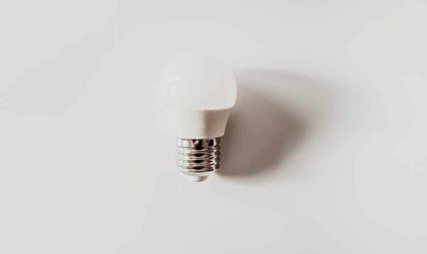 Top view of light bulb with ribbed metal cap and electrical contact on white background with shade