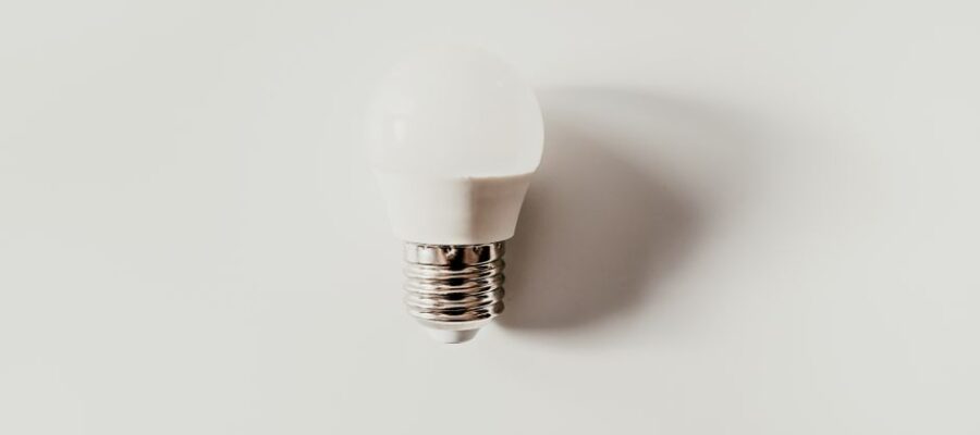 Top view of light bulb with ribbed metal cap and electrical contact on white background with shade