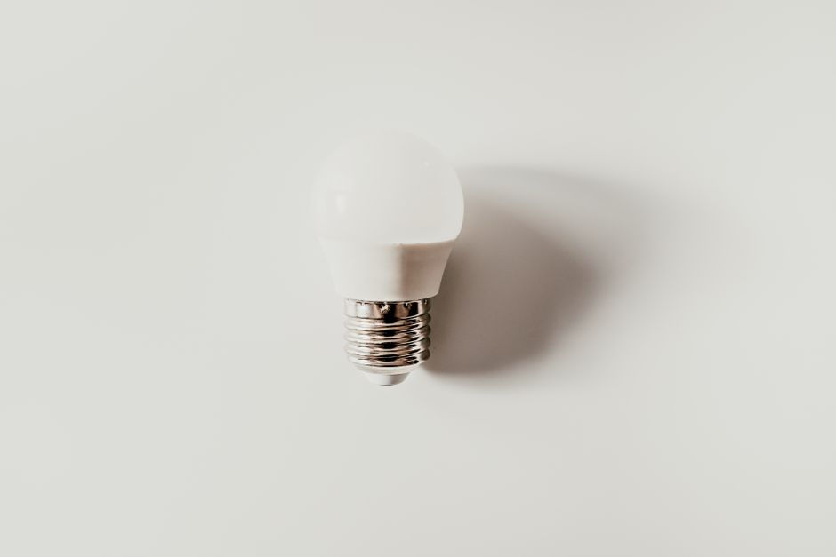 Top view of light bulb with ribbed metal cap and electrical contact on white background with shade