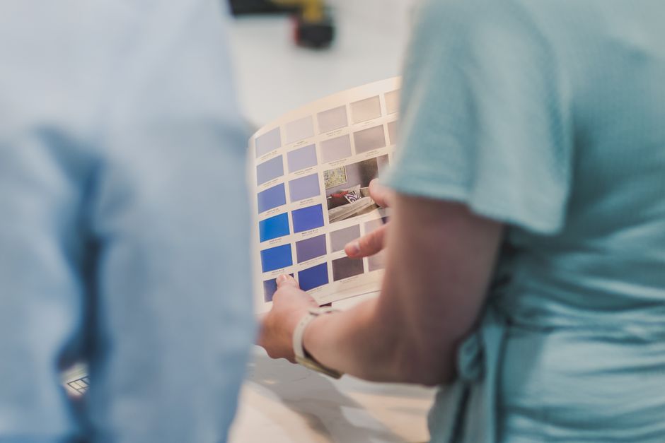 Two people reviewing a catalog of blue color samples indoors.