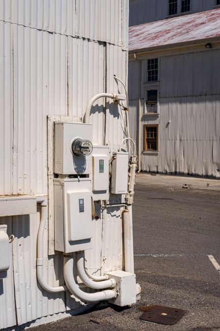Vertical shot of electricity meters and panels mounted on an industrial building exterior.