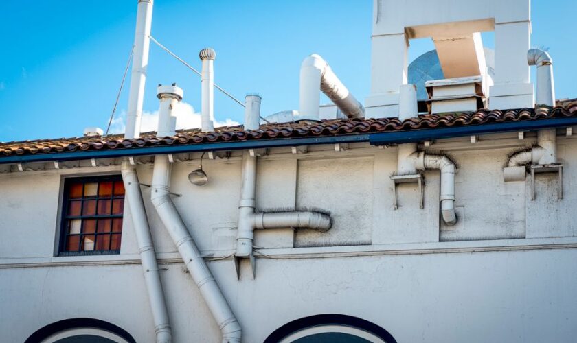 White building with chimneys and ventilation pipes on a clear day.