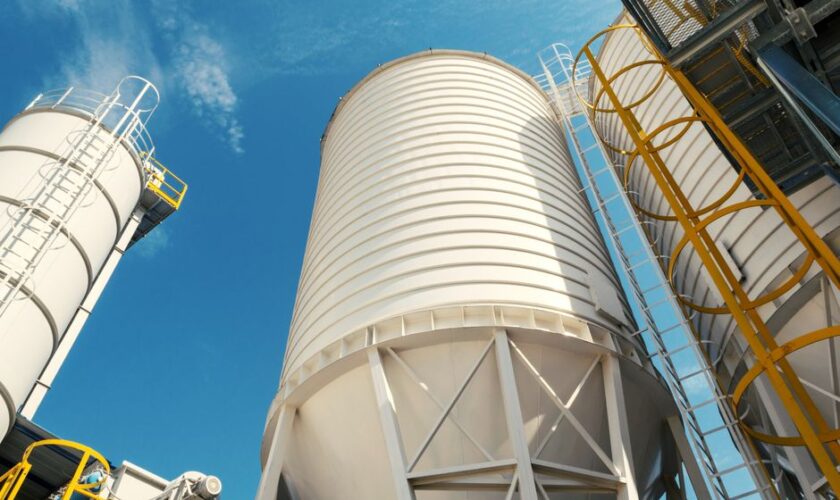Wide-angle view of industrial silos with clear blue sky, captured during daytime, showcasing modern industry.