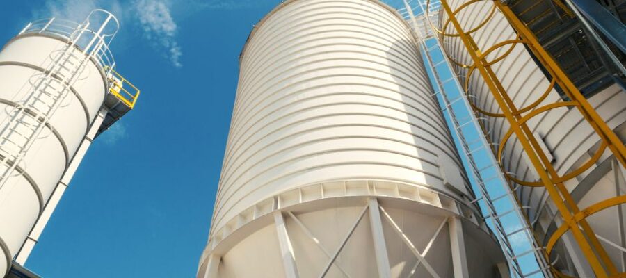 Wide-angle view of industrial silos with clear blue sky, captured during daytime, showcasing modern industry.