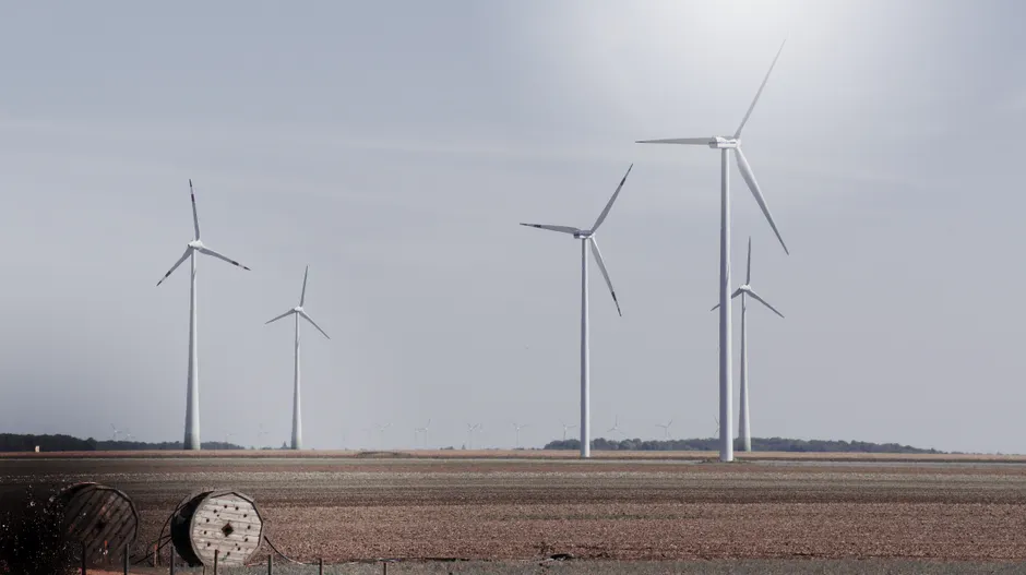 Wind turbines generating renewable energy in a vast open field under a clear sky.