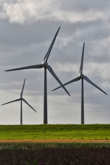 Wind turbines generating renewable energy on a grassy landscape under cloudy skies.